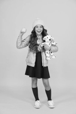 Okulda sıradan bir gün. Mutlu çocuk sarı arka planı. Soğuk mevsim için sıcak kıyafetler. Moda kızı hipster 'a benziyor. Küçük kız kış şapkası. Modayı takip eden liseli kızlar ceket ve uzun çoraplar giyer.