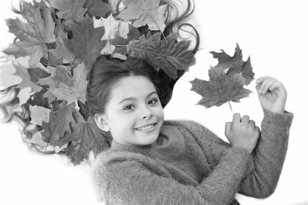 Запобігти сухому розщепленню волосся. Дитині подобається осінній сезон. Дівчинка мила дитина довге волосся лежить на білому тлі з опалим листям. Сухе кленове листя в зачісці. Концепція сезону осені. Догляд за волоссям восени — стокове фото