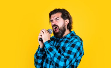 Ses egzersizi. Müzik. Olgun bir adam şarkı söyler. Ses sınıfları. Müzik tarzı. Sakallı adam mikrofonda şarkı söylüyor. Karaoke kulübündeki vahşi adam. Erkek mikrofonla şarkı söylüyor. Yakışıklı hippi partideymiş.