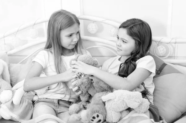 Generosity and greediness. Teach sister sharing toys. Greedy sisters. Kids play toys in bed. Little girls spend time together. Friendship sisterhood personal relations. Toys shop. Cute soft toys — Stock Photo, Image