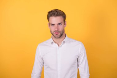 Saf güven. Turuncu arka planda genç, seksi maço. Resmi giyinmiş kendine güvenen bir iş adamı. Ofis tarzı. Erkek güzellik standardı. Sıradan bir iş adamı. Yakışıklı, tıraşsız adam beyaz gömlek giyiyor.