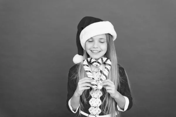 子供の頃。冬の休暇のために伝統的な縞模様のキャンディー杖。クリスマスの装飾。クリスマスの装飾のアイデア。子供サンタクロースの衣装はクリスマスのお菓子の杖を保持します。ユニークな装飾を作成する — ストック写真
