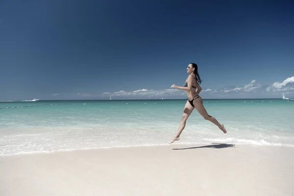 Mulher de maiô correndo na praia do mar — Fotografia de Stock