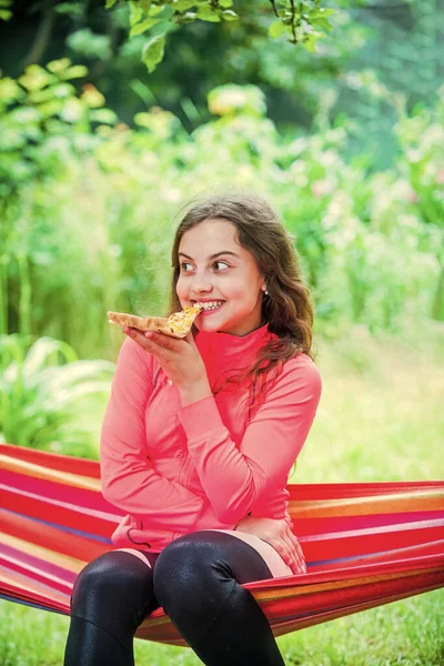 Hladová dívka jíst pizzu plátek sedět houpací síť, letní piknik koncept — Stock fotografie