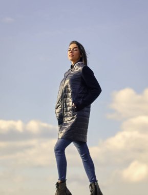 Yalnız yürüyorum. Mavi gökyüzü arka planında bir kadın. Kış tatili Uzun ceket. Hayalperest kız. Genç ve özgür bir kavram. Kıyafetlerinden daha fazlasını bekle. Kadınlar açık havada havadan hoşlanır. Güzellik ve moda