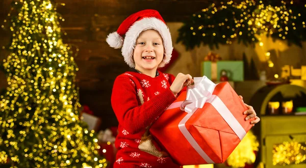 Merry christmas. Happy childhood concept. Kid wear santa hat and christmas sweater. Santa brought me gifts. December tradition. Sale discount. Real happiness. Child happy excited near christmas tree — Stock Photo, Image