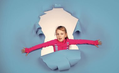 Kişisel tarzını takip ediyor. Neşeli duyguları olan bir çocuk. Kadın kuaför salonu. Güzellik ve moda. Mutlu çocuğun sıradan bir görünüşü var. Modayı takip eden çocuğun mutlu bir çocukluğu var. Mavi arka planda küçük bir kız