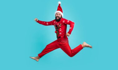 Kırmızı Noel Baba kostümlü mutlu sakallı adam koşuyor ve yılbaşı alışverişi ve yeni yıl kutlamalarıyla mutlu oluyor.
