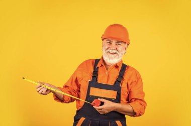 Kıdemli müteahhit ölçü olarak bant hattı kullanır. Ölçüm. Mühendis boyutu. İnşaatçı mezura tutuyor. Mühendislik ve onarım Mutlu marangoz. Duvarı boylayan tamirci.