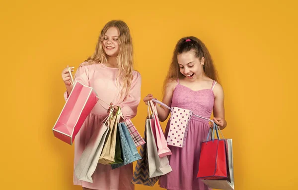 ブラックフライデーの概念です。サイバー・マンデーの子供たち。大売りだ。10代の女の子は紙袋を持ってる。プレゼントやプレゼントを買って休日に。買い物袋付きのお店の子供たちです。幸せな子供たちが買い物に行く — ストック写真