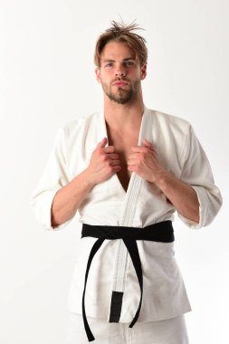 Adam siyah kuşaklı beyaz kimonoyla poz veriyor.