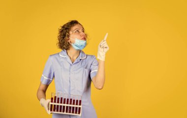 Bu çözüm doğru. Araştırmacı test tüplerini kontrol ediyor. Kadın koruyucu maske takıyor. Laboratuvar deneyi yapıyorum. Kanını test et. Yüz maskesi takan bilim adamı ve eldivenler kırmızı maddeli test tüpü tutuyor.