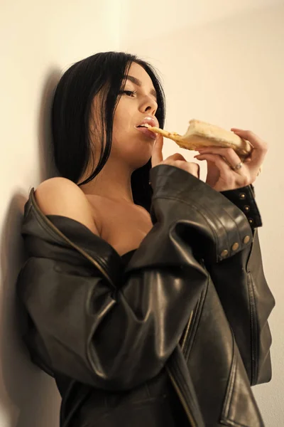 Atrakcyjna kobieta skórzana kurtka nagie ciało jedzące pizzę. Włóż kromkę do ust. Seksowna dziewczyna jedząca pizzę. Dostawa pizzy. Restauracja. Kuszące danie. Uwodzicielski posiłek. Szybkie żarcie. Apetyt seksualny — Zdjęcie stockowe