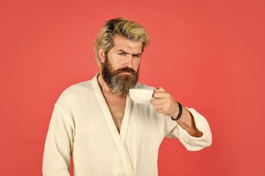 Kahvaltı konsepti. Bornozlu sakallı adam sabah kahvesinin tadını çıkar. İç çamaşırlı adam elinde kahve fincanı tutuyor. Sabah kahveyle başlar. Günlük Ritmini Anlamak. Kupalı sakallı adam.
