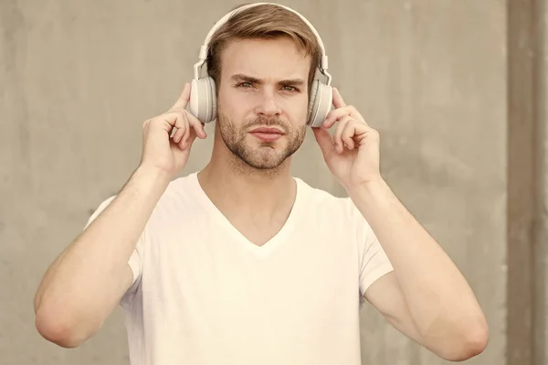 A technológia megváltoztatta a zenét. Jóképű férfi szürke fülhallgatót visel. Borotválatlan srác zenét hallgat. Új technológia. Sztereó hangtechnika. Modern zenei technológia. Modern élet — Stock Fotó