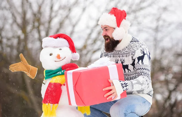 Full av lycka. Tomten ger presenter utomhus. vintersäsongens aktivitet. God jul, då. Glad hipster redo för jul. vintersemester. varm tröja i kallt väder. skäggig man bygga snögubbe — Stockfoto