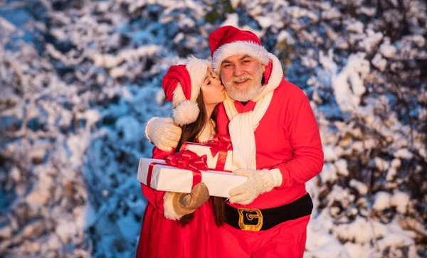 Kära tomten. Santa hjälpare med presenter utomhus. Vacker snöig vinter. barn och äldre man redo att fira semester. vintersemester och semester. Morfar i tomtedräkt med liten flicka — Stockfoto