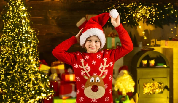 Dezember-Tradition. Lieblingstag des Jahres. Kind glücklich aufgeregt neben Weihnachtsbaum. Frohe Weihnachten. Glückliche Kindheit. Kinder tragen Weihnachtsmütze und Weihnachtspullover. Der Weihnachtsmann brachte mir Geschenke — Stockfoto