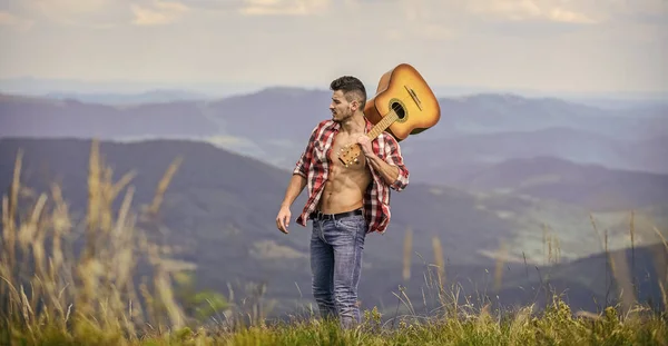 Música verdadeira. homem sexy com guitarra em camisa quadriculada. moda hipster. camping ocidental e caminhadas. feliz e livre. Homem cowboy com tronco musculoso nu. guitarrista acústico. música country — Fotografia de Stock