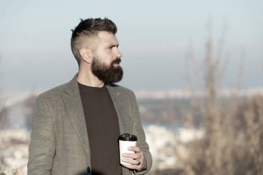 Kafein bağımlısı. Hippi bardağı kafein enerji içeceğiyle birlikte tutar. Sakallı adam açık havada sıcak kafeinli içecekle şarj oluyor. Sabah kafeinle daha iyi olur.