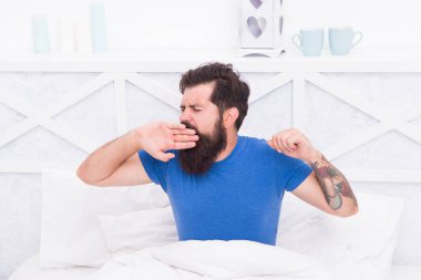 Hoş bir uyku saati. Vahşi erkek odada vakit geçiriyor. Rahat yaşam tarzı konsepti. Sakallı adam yatakta esniyor. Sabah uyanırsın. Bekar rahat hisset. Yatak odasında esneyen adam. Tembel Pazar