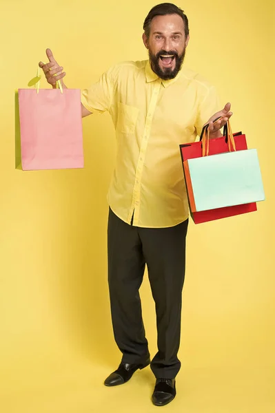 Sigue sonriendo y sigue adelante. Hombre feliz sostiene bolsas de compras de fondo amarillo. Venta de despacho de temporada. Venta y entrega. Ropa de hombre a la venta. Compra moda. Porque su venta, espacio de copia — Foto de Stock