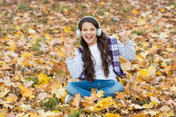気が狂ってる。子供の頃の幸せ。美しさと自然。幸せな子供はヘッドフォンを着用する。10代の女の子は学校に行く途中で音楽を聴く。子供は秋の森でリラックス。公園にもみじの葉が落ちる。オンライン教育 — ストック写真