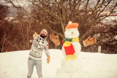 Sırada sen varsın. Mutlu hipster Noel 'i kutlamaya hazır. Sakallı adam kardan adam yapar. Kış tatili açık havada. Soğuk havada sıcak kazak. Adam karla oynuyor. Kış mevsimi aktivitesi. Noel 'i