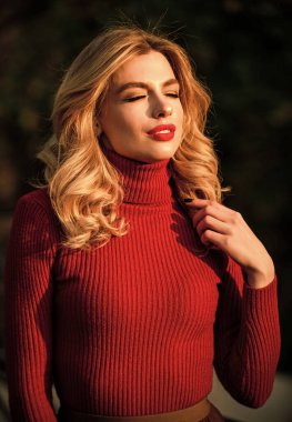 Sevimli kız geçen güneş ışınlarının tadını çıkarıyor. Şık kıyafetler. Kadınlık ve şefkat. Sonbahar tarzı kıyafetler. Sonbahar modası. Sonbahar parkında yürüyen bir kadın. Samimi örgü giysiler. Örgü süveter
