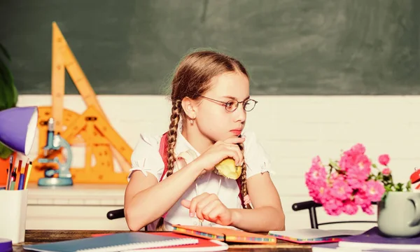 Υγιεινός τρόπος ζωής Σνακ ανάμεσα στα μαθήματα. Σχολική ζωή. Σύγχρονη παιδική ηλικία. Σχολικές διακοπές. Μαθήτρια κάθεται γραφείο chalkboard φόντο. Μαθητής στο σχολείο. Κορίτσι μικρό παιδί τρώει μηλόπιτα — Φωτογραφία Αρχείου