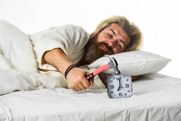 La paralisi del sonno può verificarsi anche quando si è in procinto di svegliarsi. Concetto di rabbia. Devo rilassarmi. Gli hipster barbuti vogliono dormire. Fasi del sonno. L'uomo si sveglia infelice con l'anello della sveglia. Dormi più a lungo — Foto Stock