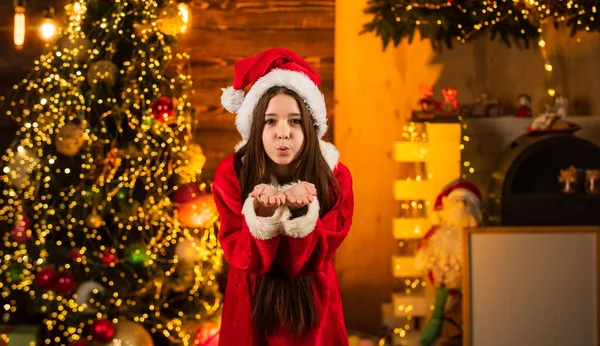 Envía besos aéreos. Felicidad y alegría. Niño feliz chica emocionada y regalos cerca del árbol de Navidad. Feliz navidad. Concepto de infancia feliz. Sombrero de Santa Claus. Hora del milagro. Difundir amor. Actividades de diciembre —  Fotos de Stock