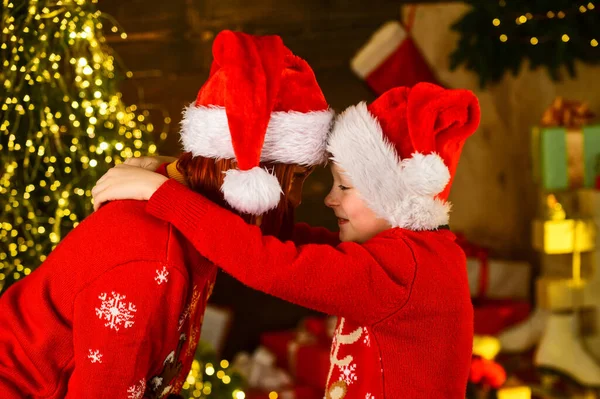 Nochebuena impecable. La rutina de la mañana de Navidad para las madres. Mamá abrazando a su hijito cerca del árbol de Navidad. Concepto familiar feliz. Objetivos de paternidad. Una simple felicidad. Mamá te quiere. Momentos de Navidad — Foto de Stock