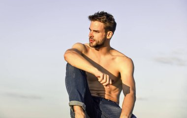 Küçük bir mola. Kaslı vücutlu genç bir atletik. Sporcu ve fitness modeli. Çıplak ve güçlü bir adam. Güçlü kaslı adamın yüzünde kıllar var. Atletik vücut şekli. Tişörtsüz adam, gün doğumunda rahatla.