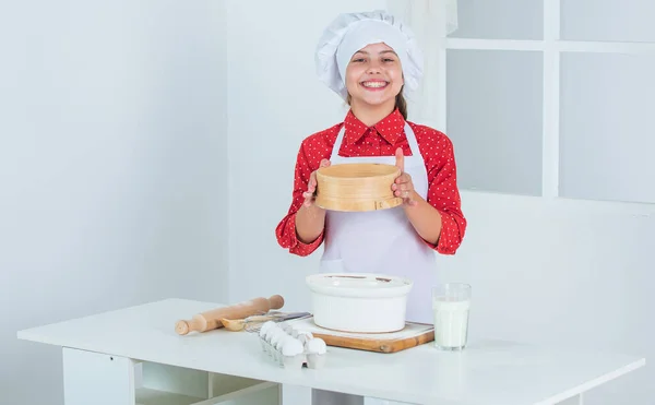 좋은 하루되 세요. 전문적 이고 숙련 된 제빵사죠. 셰프 복장에 모자쓴 애. 반죽을 준비하는 십 대 소녀. 레시피로 케이크를 만드는 것입니다. 먹을 시간이야. 부엌에서 요리하는 행복 한아이. 부엌에 있는 빵 쿠키 — 스톡 사진