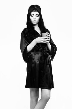 Siyah ipek elbiseyle fincanla poz veren seksi kız