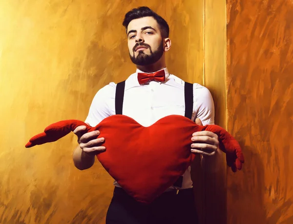 Brodaty mężczyzna trzymając czerwone pluszowe serce z poważną twarzą — Zdjęcie stockowe