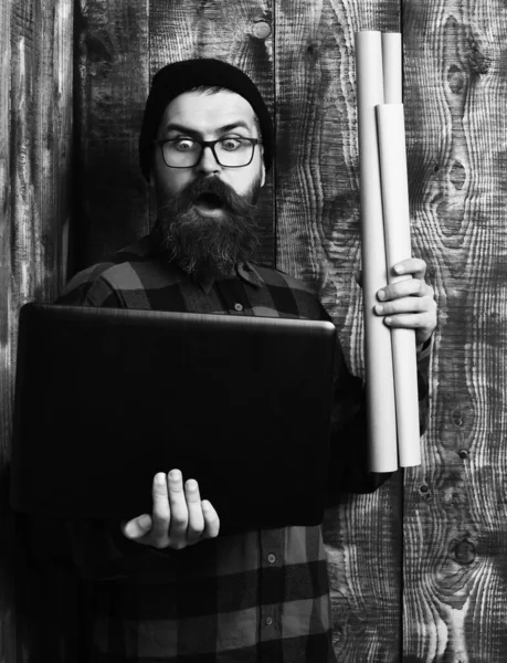 Bearded brutal caucasian hipster holding laptop and craft paper