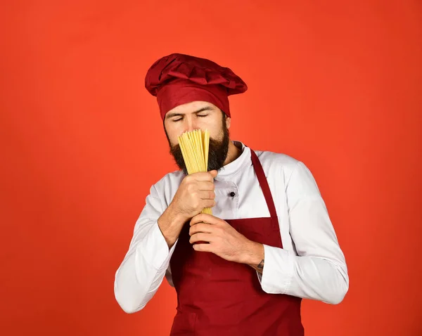 Cook with hidden dreamy face holds dry pasta