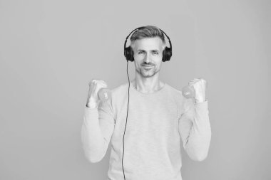 Olgun bir adam mavi üzerine izole edilmiş spor eğitimi yapar. Dambılı bir sporcu. Müzikli spor salonu. Spor salonu. Atletik egzersiz için müzik. Güçlü sporcu adam seni. Sportmenlik.