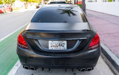 Miami, Florida, ABD - 07 Nisan 2025: Lüks siyah mat Mercedes Benz C W205. Mercedes Benz C W205 dışarıda park halinde. Siyah mat araba, arka manzara. Mercedes Benz C W205 arabası.