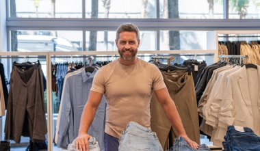 Designer clothing. Jeans in luxury store. Luxury shopping for a stylish man. Male fashion shop. Stylish man in menswear boutique. Mature man choosing jeans.