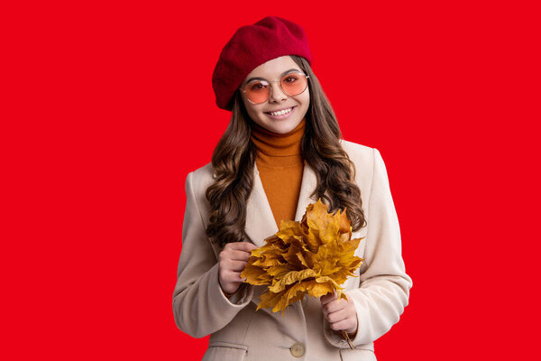 Autumn leaves in hand teen girl. Autumn leaves and teen young girl isolated on red. Teenager girl in autumn beret. Fall leaves. Girl in fall style. Fall style fashion.