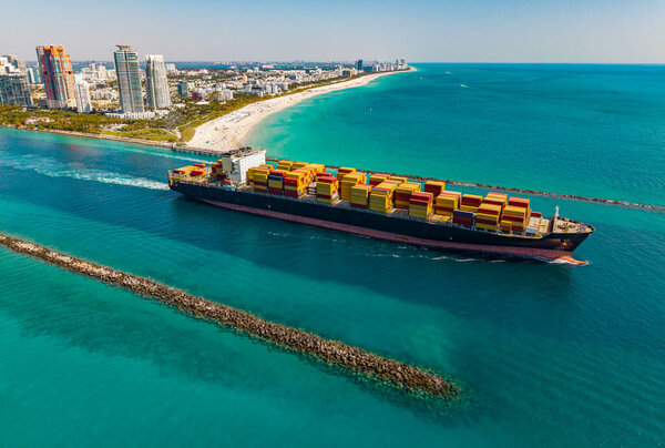 Грузовой контейнер загружен на грузовое судно. Воздушный корабль с контейнером. Грузовой бизнес. Контейнерный корабль. Доставка логистики. Коммерческая доставка. Грузовой корабль в море, вид с воздуха. Грузовая палуба.