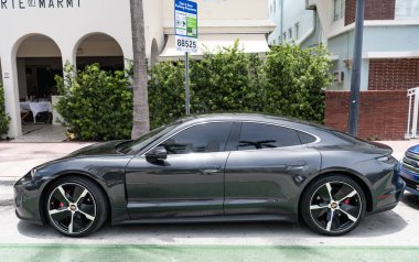 Miami, Florida, ABD - 12 Temmuz 2025: Porsche Taycan 2020 elektrikli araba. Lüks elektrikli Porsche Taycan. Porsche Taycan dışarıda park etmiş. Siyah elektrikli araba, yan görüş..