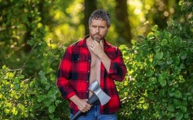 Strong man work in forest. Man in forest with axe. Lumberjack carries axe. Deforestation. Mature sweating man with axe. Lumberjack in woods with ax. Lumberjack tired with heavy axe. Forest cutter.