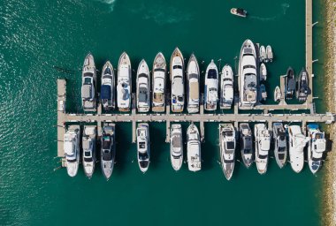 Marinaya yanaşmış lüks yatların havadan görüntüsü. Yatların yukarıdan aşağıya insansız hava aracı görüntüsü. Tekneler ve yelkenliler Manzaralı deniz kıyısında
