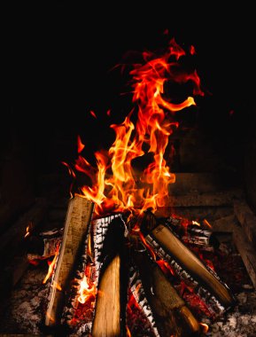 Yanan şenlik ateşi. Koyu bir arka planda alev dilleri. Yanan ahşap kütükler. Arkaplan fotoğrafı.