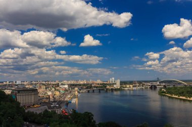 Yaz şehri manzarası. Gökyüzünün altında bulutlu büyük bir nehir var. Kyiv 'deki Dinyeper Nehri. Kyiv 'in tarihi merkezi.