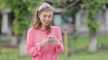 Kadın caddede cep telefonunu kontrol ediyor..